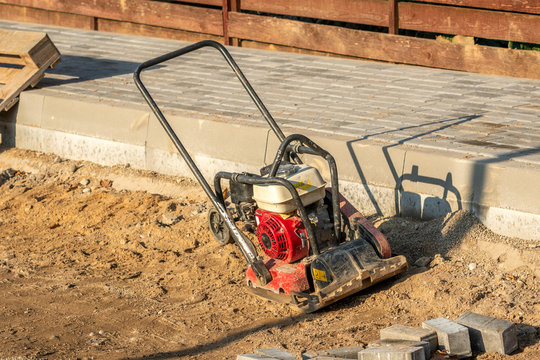 Vibratory plate compactor on pavement works