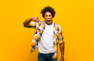 young black man pointing at camera with an angry aggressive expression looking like a furious,...