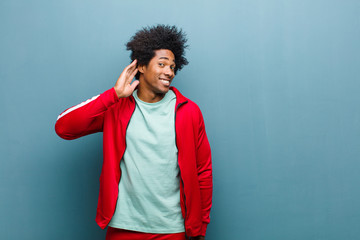 young black sports man looking serious and curious, listening, trying to hear a secret conversation...