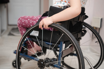 close-up hand of a child on a wheel from a wheelchair. Disabled children concept.