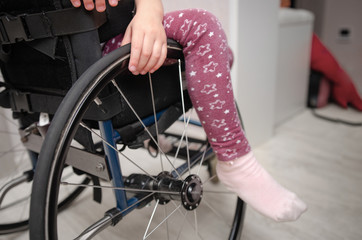 close-up hand of a child on a wheel from a wheelchair. Disabled children concept.