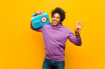 young african american man with a vintage radio against orange b