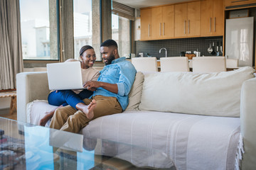 Smiling African American couple using a laptop together at home