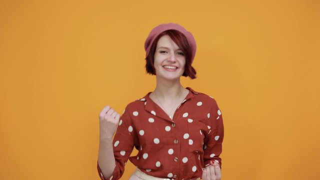 Attractive brunette woman wearing funny pink hat over isolated background celebrating surprised and amazed for success with arms raised and open eyes. Winner concept.
