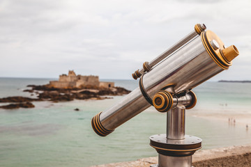Obraz na płótnie Canvas Tourist monocular telescope on the terrace of Saint Malo opposite the Fort National fortress