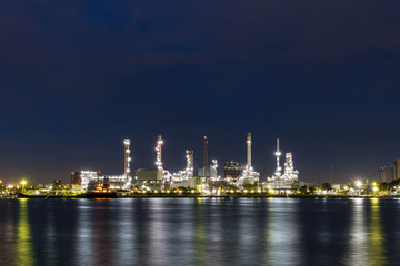 Oil refinery at night petrochemical and energy industry with refection on river