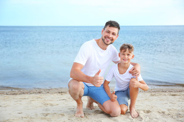 Portrait of happy father and son on sea beach