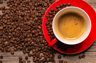 Red cup of aromatic black coffee on a wooden table.