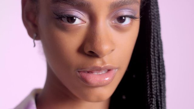 closeup mixed race woman portrait showing her shny lilac eye makeup. Mixed race deep skintone makeup