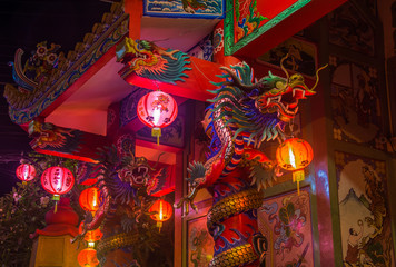 Traditional Chinese Temple with dragons and lights on columns in the night on koh Samui