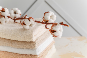 Soft clean towels with cotton flowers on table - obrazy, fototapety, plakaty