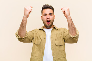 young hispanic man celebrating an unbelievable success like a winner, looking excited and happy...