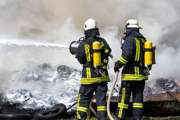 Feuerwehr löscht mit Wasser und Schaum brennende Reifen