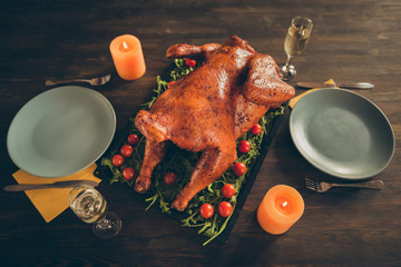 Top above high angle photo of big tasty roast chicken on tray with red cherry tomato herbs served...