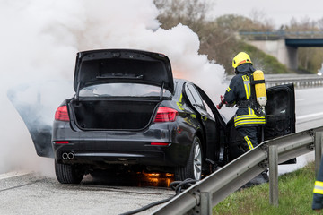 Obraz na płótnie Canvas Feuerwehrmänner löschen ein brennendes Auto