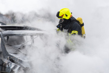 Feuerwehrmänner löschen ein brennendes Auto