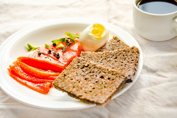 Slices of Salted Raw fish fillet with egg and piece of buckwheat gluten-free bread.  Paleo diet meal. Healthy high protein and low carbohydrate products concept