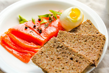 Slices of Salted Raw fish fillet with egg and piece of buckwheat gluten-free bread.  Paleo diet meal. Healthy high protein and low carbohydrate products concept