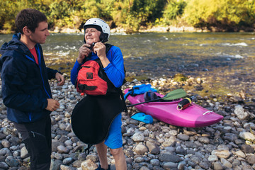 Senior man preparing for kayak tour on a mountain river.