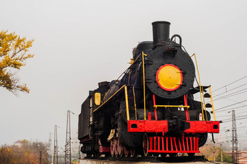 Fototapeta premium Old steam train on rails near the railway station in the fall.