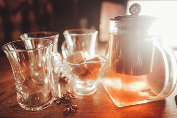 hot tea in a clear teapot and three cups on the table. nobody.
