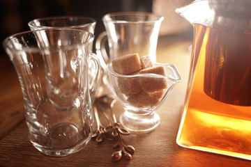 hot tea in a clear teapot and three cups on the table. nobody.