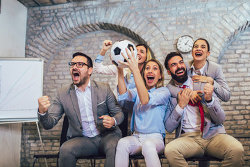 Happy business people or football fans watching soccer on tv and celebrating victory. Friendship, sports and entertainment concept. © Mediteraneo