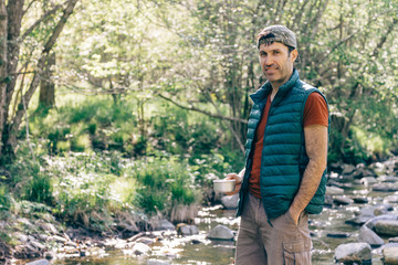 Hiker drinking water in a creek in the middle of the forest