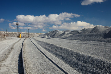 Gravel storage near the quarry for limestone mining. Piles of fine gravel on a background of blue...