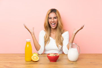 Young blonde woman having breakfast milk unhappy and frustrated with something