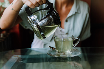 Fototapeta na wymiar Woman pouring herbal tea into a glass cup