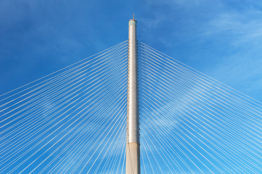 Fototapeta Rope and pylon of modern suspension bridge against blue sky. Building abstract background