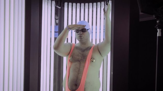 Full man sunbathes in tanning beds and dances.