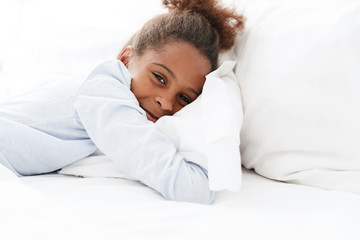 Image of brunette african american little girl lying in bed at home