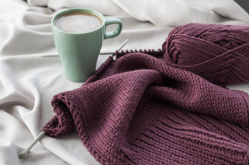 Cup of coffee on the background of burgundy knitting
