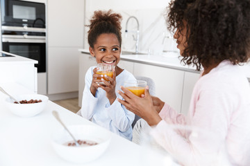 Image of american woman and her daughter having breakfast at home