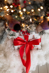 Gift with a red ribbon under the Christmas tree artificial snow. surprise from santa claus . New Year's morning