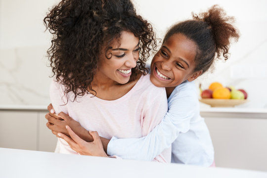 Image of african american woman and her little daughter hugging at home