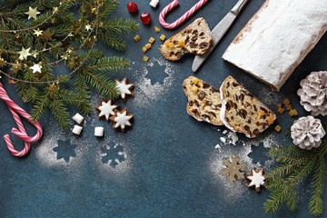 Christmas festive background with german traditional Stollen, cookies,  fir branch, cones and  spices. Overhead view. Copy space
