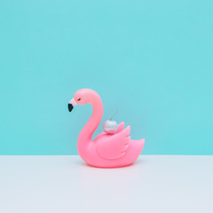 Silver decoration ball on plastic pink flamingo bird on white and light blue background. Christmas and new year concept. Winter holidays composition.  Minimalism