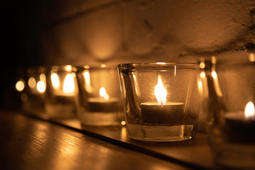 Line of votive candles and tea lights in a row with candlelight
