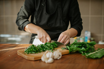 Closeup of female chef's hands preparing a recipe in the kitchen with vegetables. Woman cook...