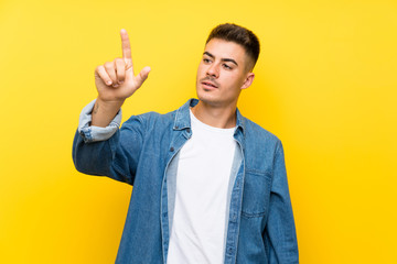 Young handsome man over isolated yellow background touching on transparent screen