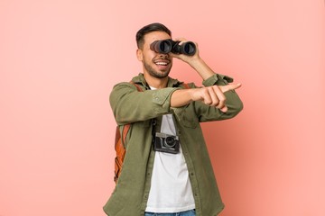 Young south-asian man looking through a binoculars.