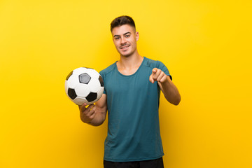 Handsome young football player man over isolated yellow background points finger at you with a...