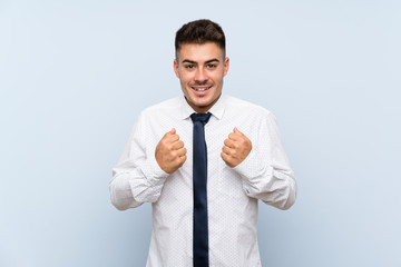 Handsome businessman over isolated blue background celebrating a victory