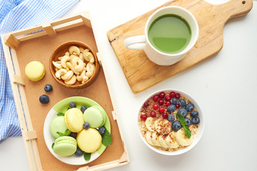 matcha green tea, breakfast top view white background. oatmeal with berries, toasts on a wooden tray, nuts, coffee