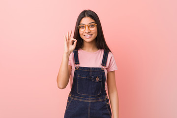 Young pretty arab woman wearing a jeans dungaree cheerful and confident showing ok gesture.