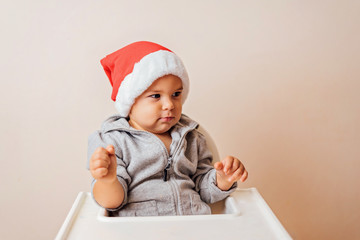 baby in Christmas bonnet looks at camera, on white background