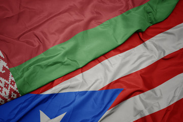 waving colorful flag of puerto rico and national flag of belarus.